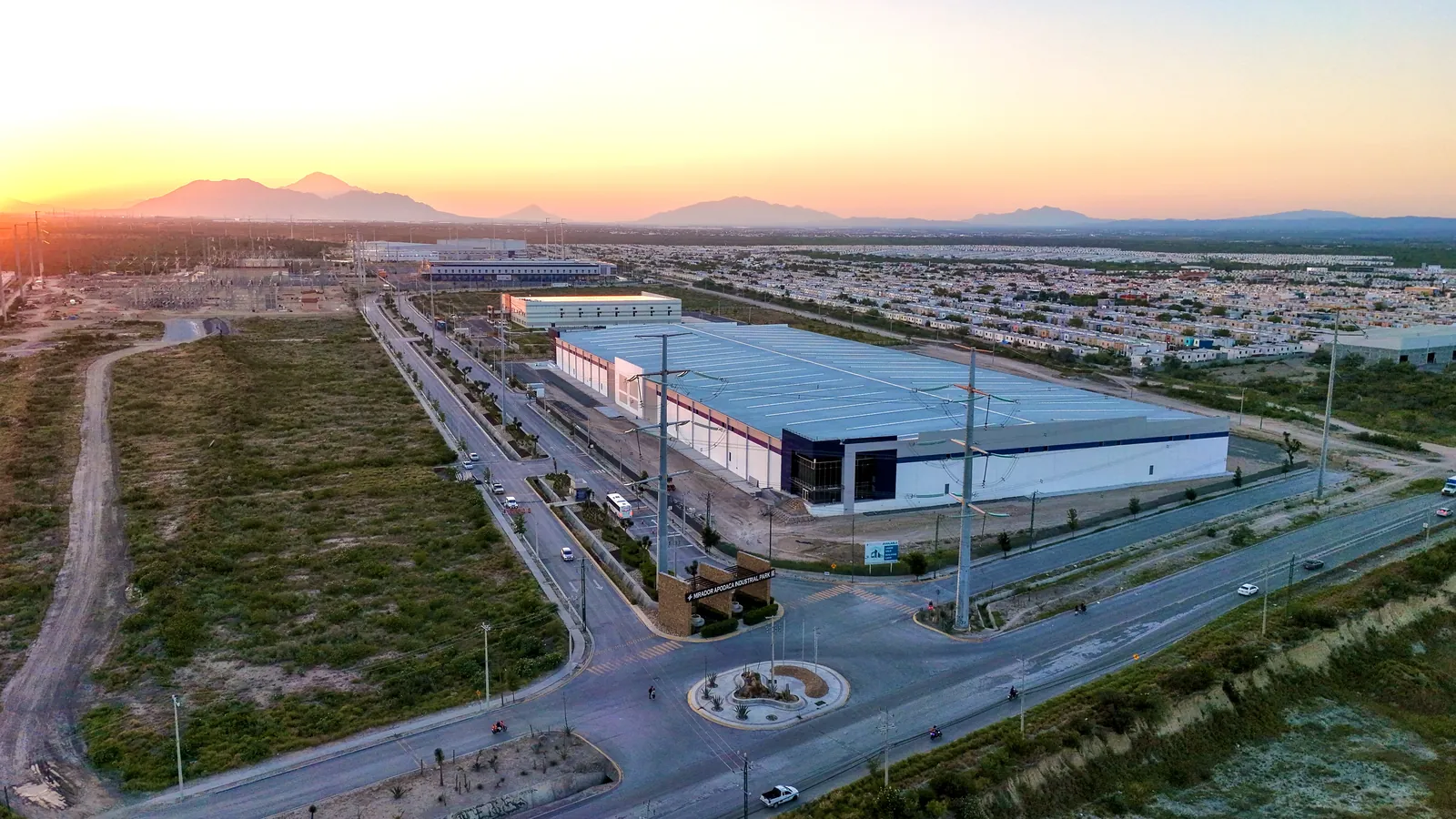 Mirador Apodaca al atardecer — nave industrial con andenes de carga y vialidades del parque, Apodaca, Nuevo León